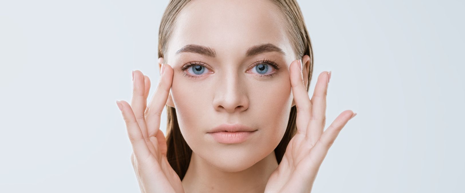 woman with blonde hair touching her face